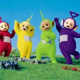 Tinky Winky, Dipsy, Laa-Laa i Po, czyli Teletubisie, machają radośnie na zielonej łące.