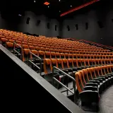 Puste rzędy pomarańczowych foteli kinowych. Czy to sala 4DX?