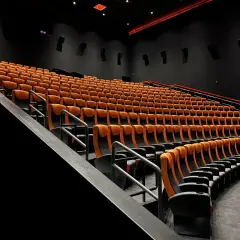 Puste rzędy pomarańczowych foteli kinowych. Czy to sala 4DX?