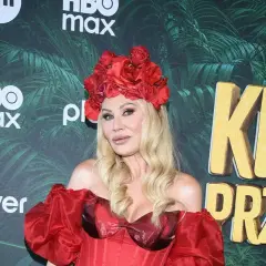 Monika Jarosińska w czerwonej kreacji i wianku z róż na głowie, na tle napisu "Król przetrwania".