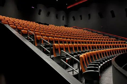 Puste rzędy pomarańczowych foteli kinowych. Czy to sala 4DX?