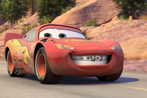 Błyskawica McQueen z "Auta 4" na drodze. Jego uśmiech zdobią owady, a na karoserii widać ślady przygód.