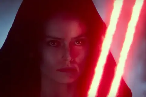 Rey w kapturze, z intensywnym spojrzeniem, trzyma podwójny czerwony miecz świetlny.
