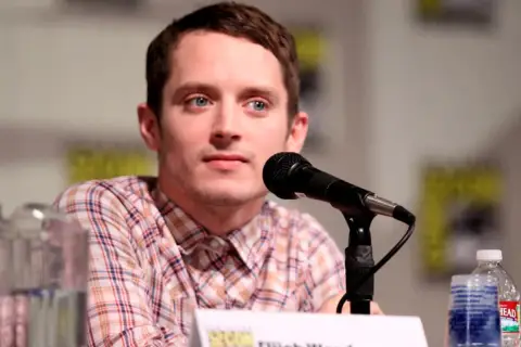 Elijah Wood, znany z wielu filmów, siedzi przy mikrofonie.