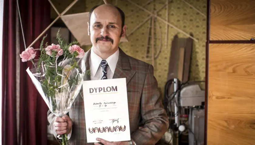Adam Woronowicz z bukietem i dyplomem, jakby po premierze jednego z jego filmów.