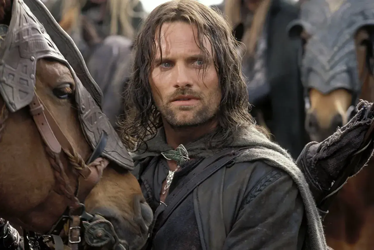Viggo Mortensen jako Aragorn, w otoczeniu koni i innych postaci, w scenie z jednego z jego filmów.