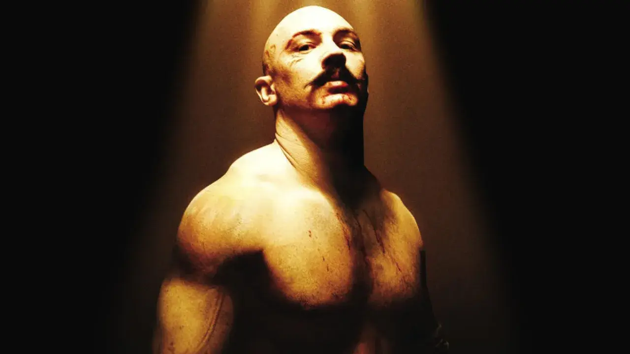 Tom Hardy jako Bronson, w stylu filmów Charlesa Bronsona. Zgolona głowa, wąsy i blizny.