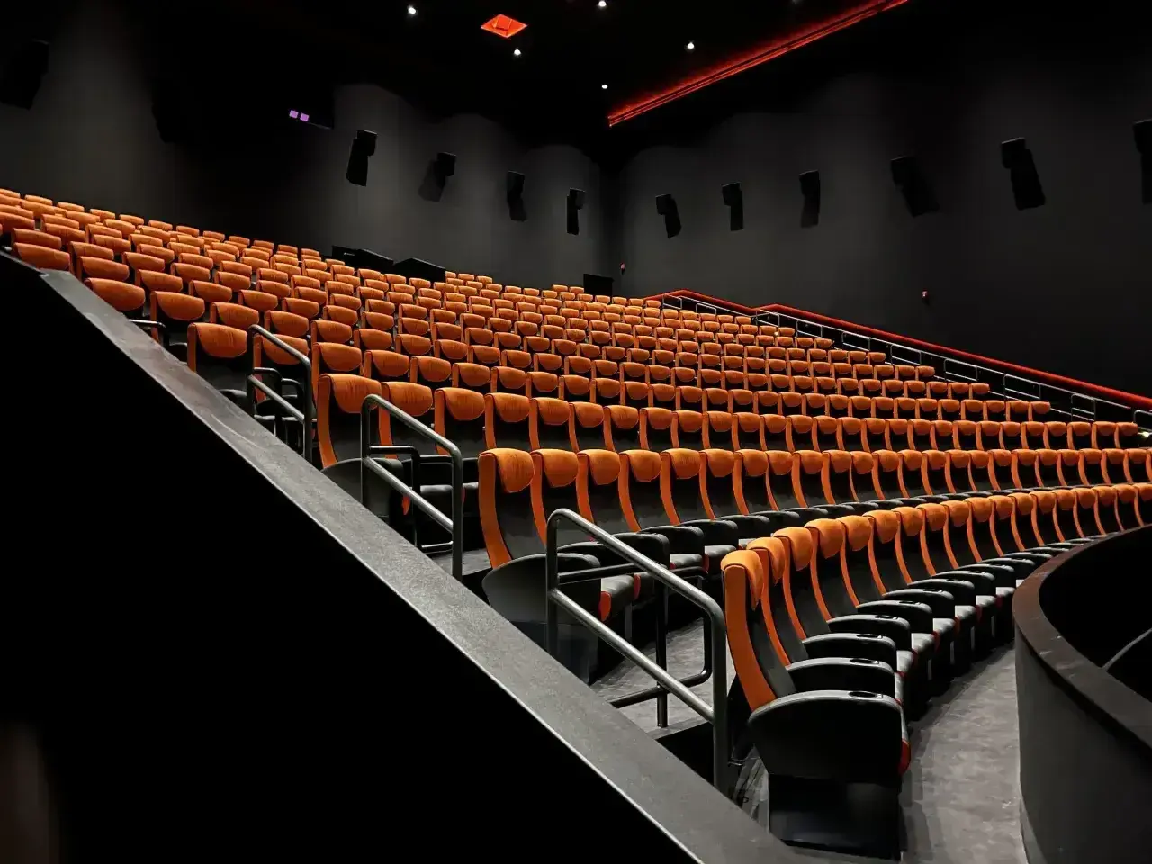 Puste rzędy pomarańczowych foteli kinowych. Czy to sala 4DX?