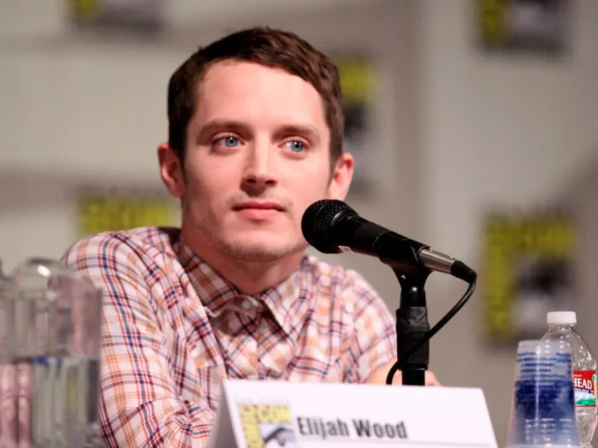 Elijah Wood, znany z wielu filmów, siedzi przy mikrofonie.