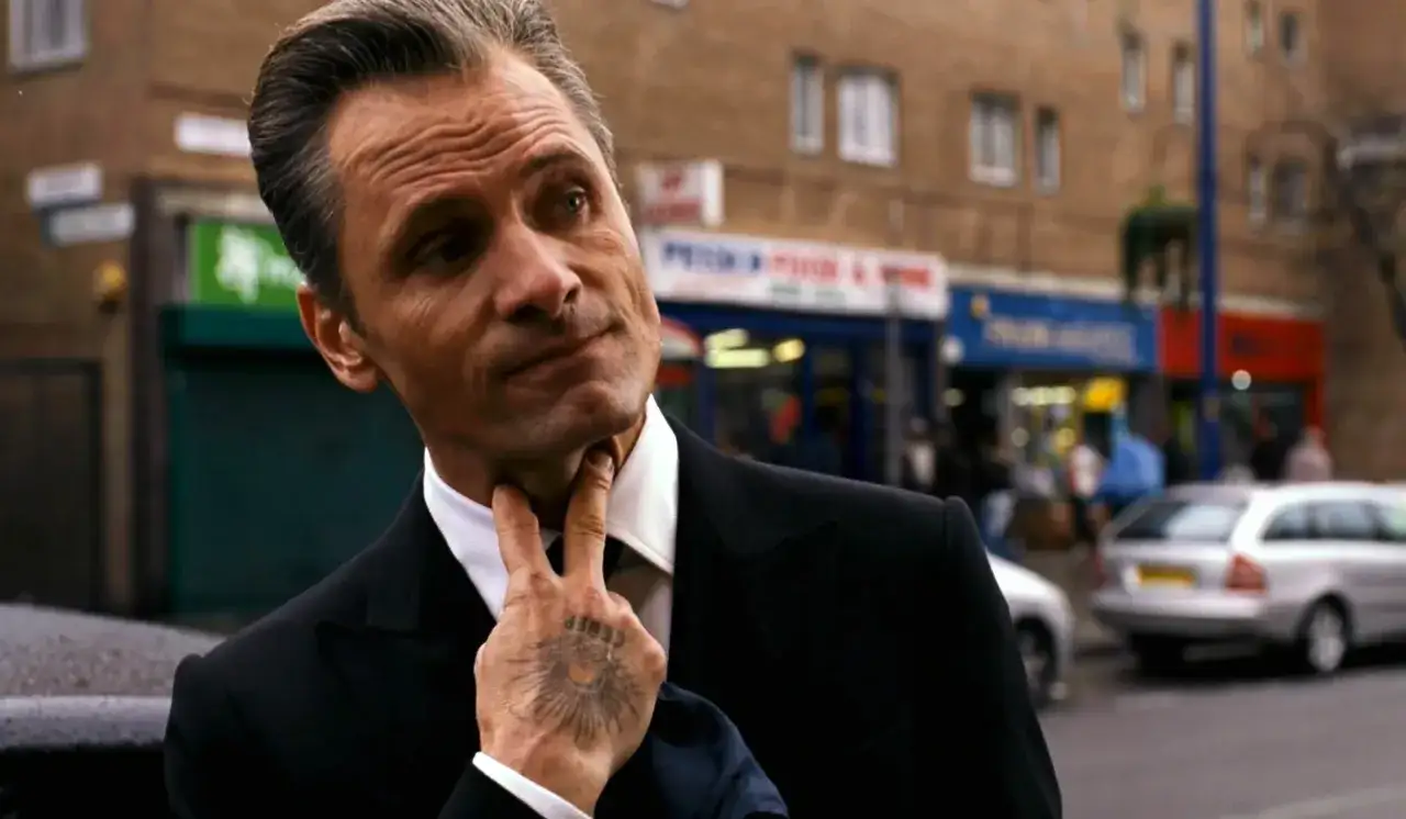 Viggo Mortensen w eleganckim garniturze, z charakterystycznym tatuażem na dłoni, przypomina o jego niezapomnianych rolach w kinie.