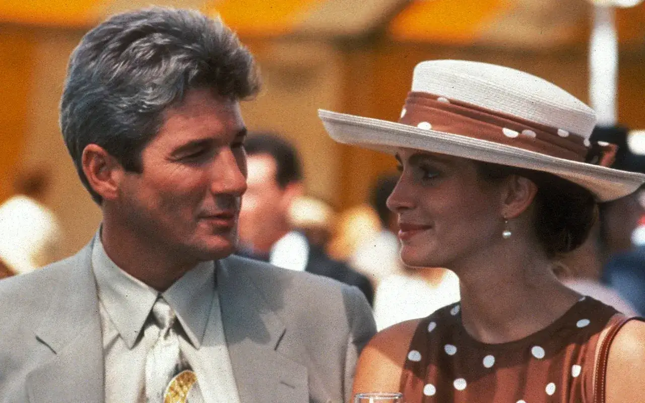 Elegancki mężczyzna i pretty woman 2 w kapeluszu z kokardką i kropkami, patrzą na siebie z uśmiechem.