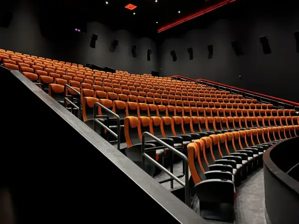 Puste rzędy pomarańczowych foteli kinowych. Czy to sala 4DX?